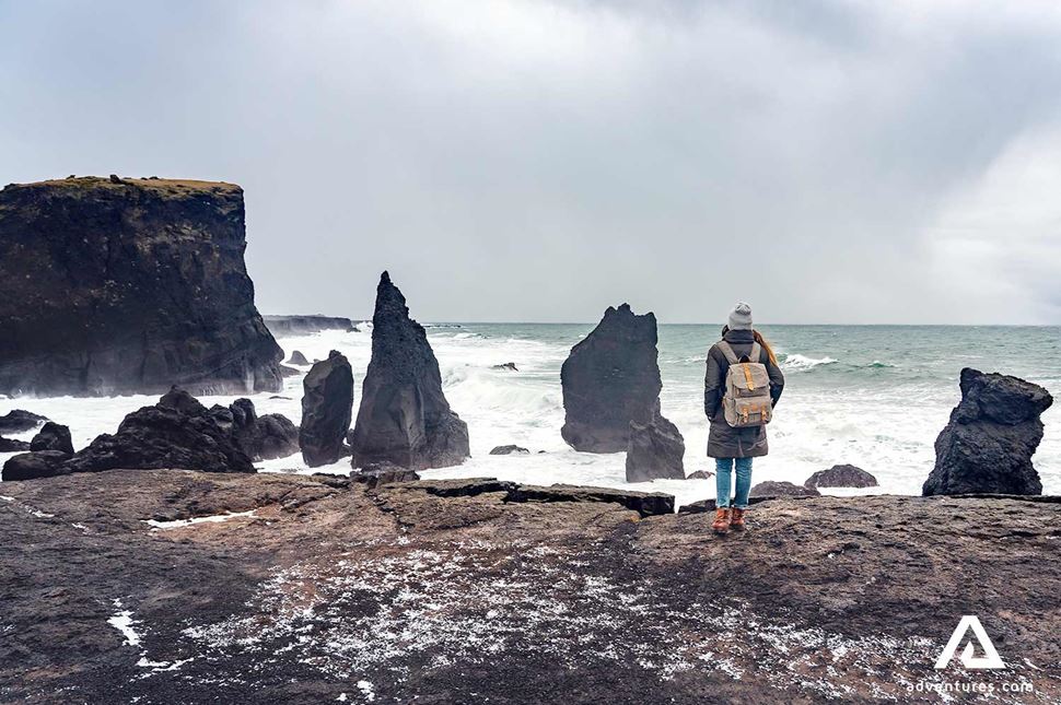 woman walking near sea stacks in reykjanes in iceland