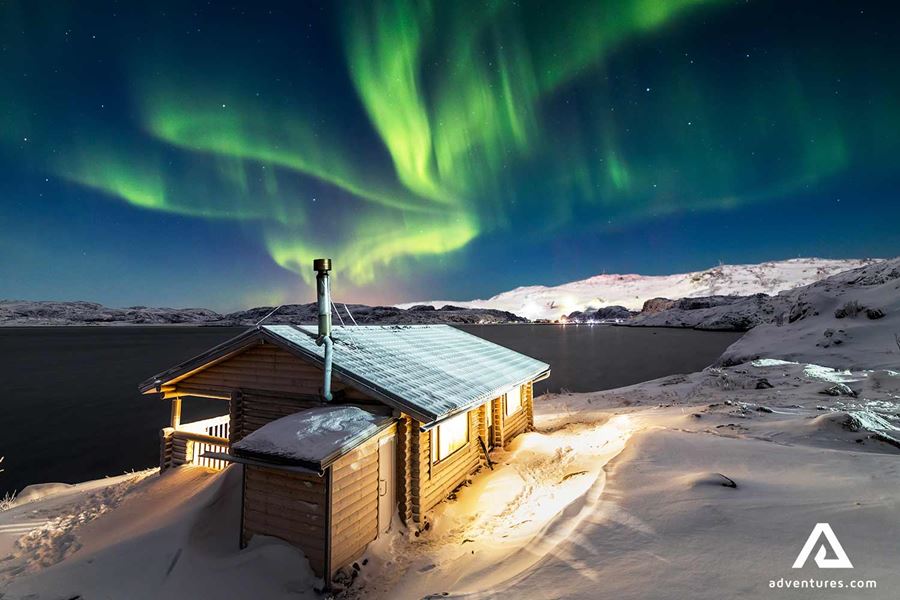 wooden cabin in winter near northern lights