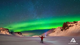 man with a flashlight watching northern lights in winter