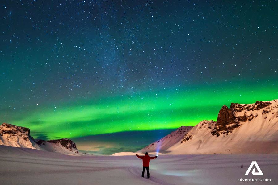 man with a flashlight watching aurora