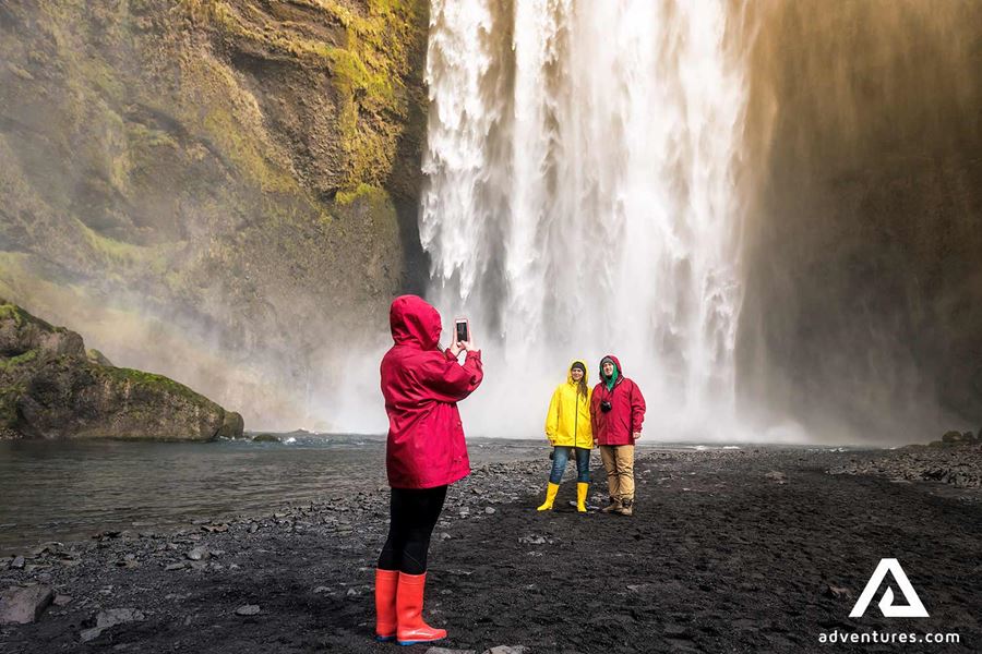 happy people taking pictures near skogafoss
