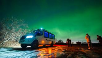 People Standing Next To 4X4 Sprinter Under Northern Lights