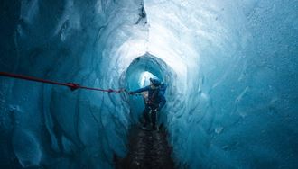 Glacier guide exploring ice cave