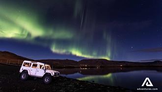 land rover jeep near northern lights in iceland