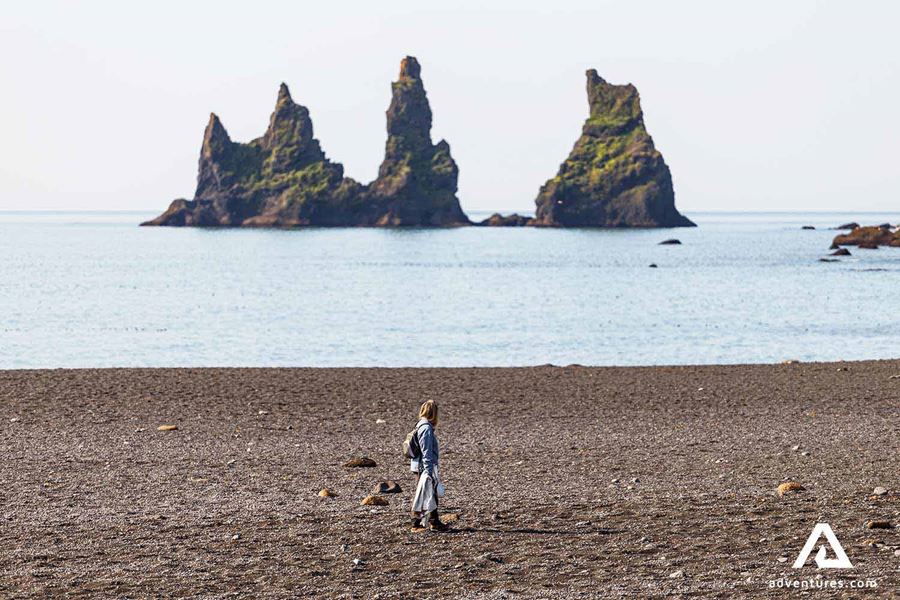 woman walking close to reynisdrangar