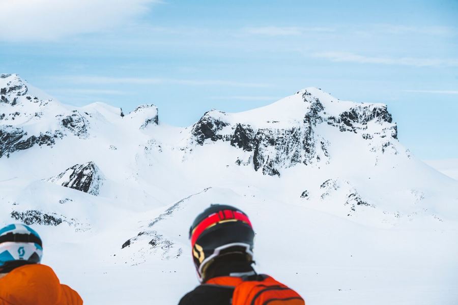Snowmobiling duo wearing safety helmets standing in front of Langjokull glacier.
