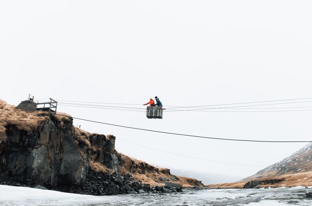 People crossing river with cable bridge
