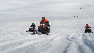 People Riding Snowmobiles On Glacier