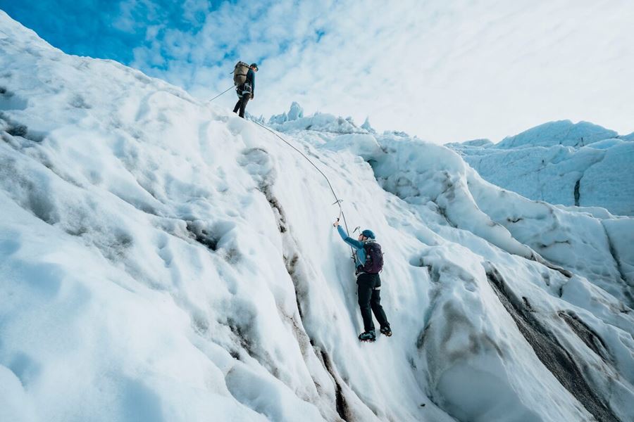 Duo ice climbing at Vatnajokull glacier with bright blue skies.