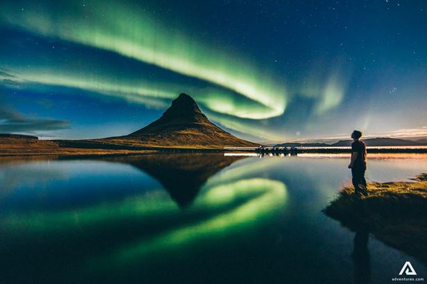 A man watching northern lights at night in Snaefellsnes Peninsula