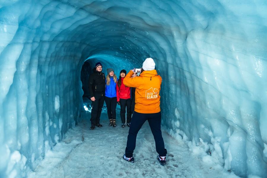 Tour guide taking a photo of a small group inside glacier ice tunnel in Iceland 
