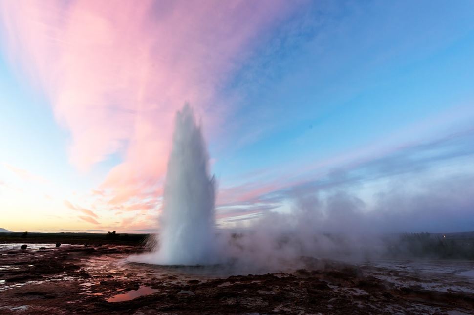 Strokkur geyser in Geysir area of Iceland with pink sunset skies 
