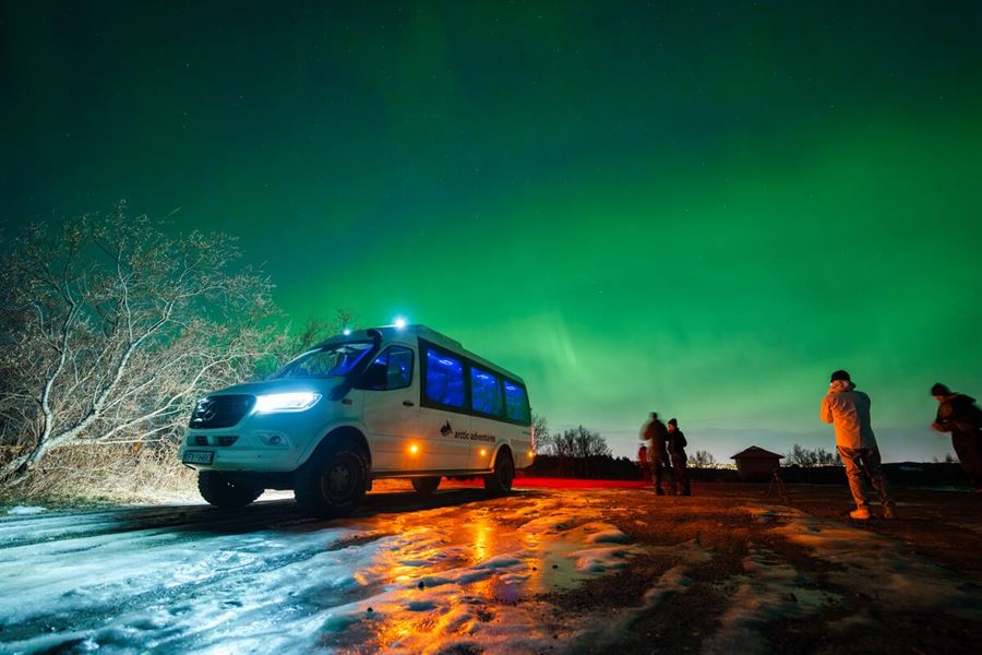 People Standing Next To 4X4 Sprinter Under Northern Lights