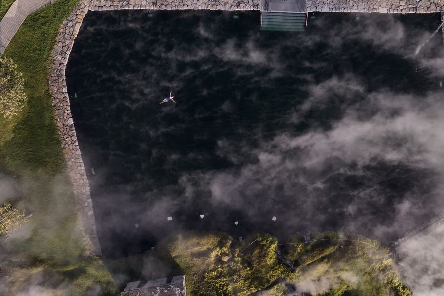 Ariel view of secret lagoon geothermal pool with lady floating and relaxing 