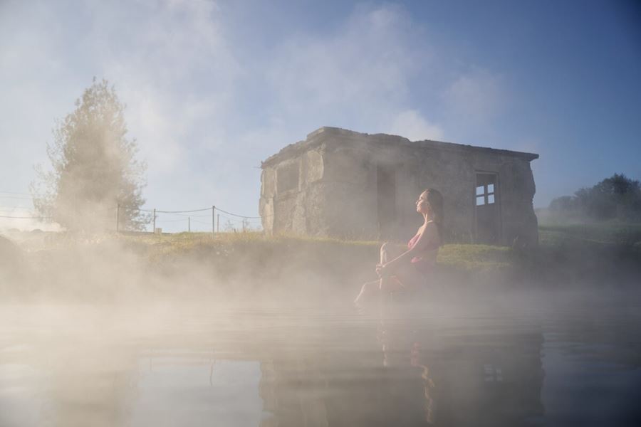 Steamy secret lagoon with lady relaxing on bank next to pool