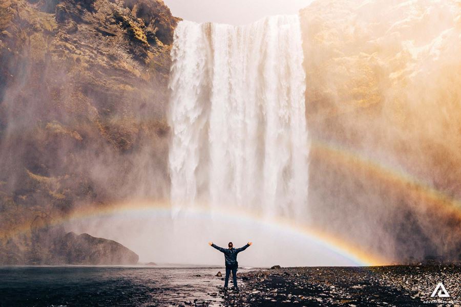 Raised hands person standing near Skogafoss Waterfall
