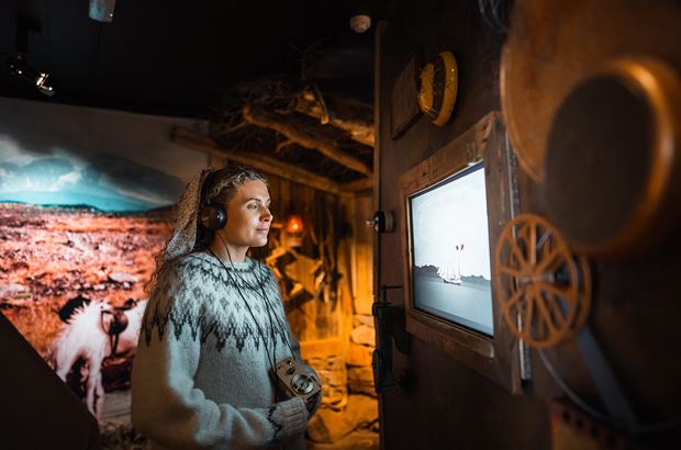 Lady with headphones listening at Wilderness Museum in Iceland.