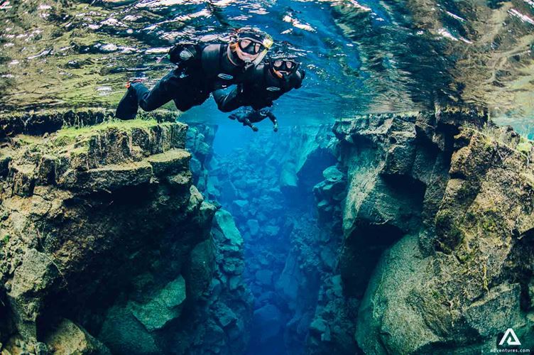 Three People Snorkeling Silfra Fissure In Iceland
