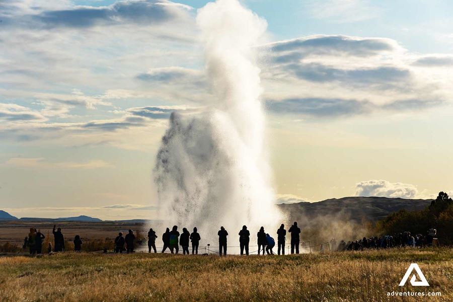 group of people sightseeing around geysir