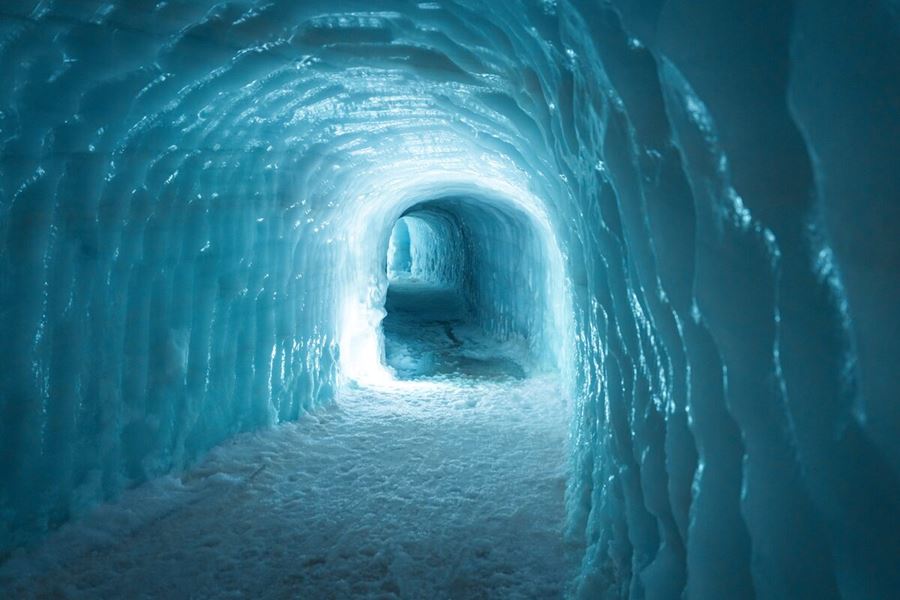 Blue ice walls of Langjokull glacier ice tunnel with light reflecting 