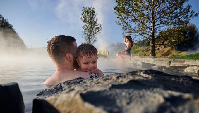 Family in secret lagoon pool, father and child  hugging and mother swimming 