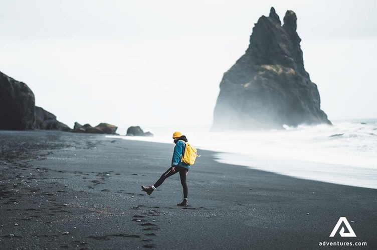 man walking around reynisfjara black sand beach