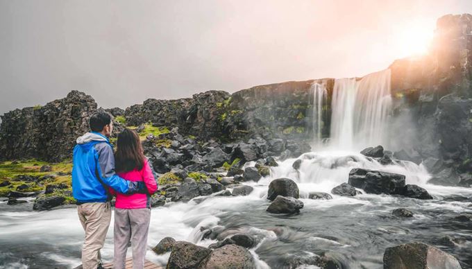 a couple standing close to oxararfoss waterfall