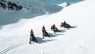 Four Snowmobiles And Their Drivers On Snowy glacier In Iceland